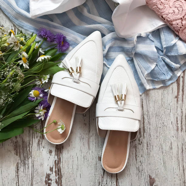 istock White sandals with flowers on a wooden background 1069136094
