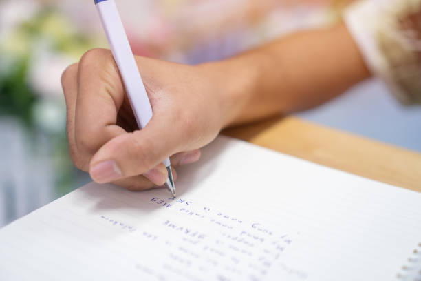 istock Man student taking and writing notes on notebook with pen in library at college university for homework. Education learning studying in school concept 1069150754