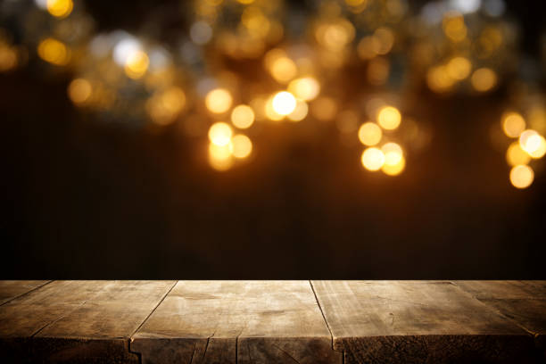istock rustic wooden table in front of glitter black and gold bokeh lights. 1069151666