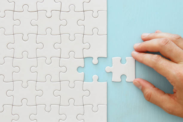 istock male hand putting the last piece in the puzzle. 1069151668