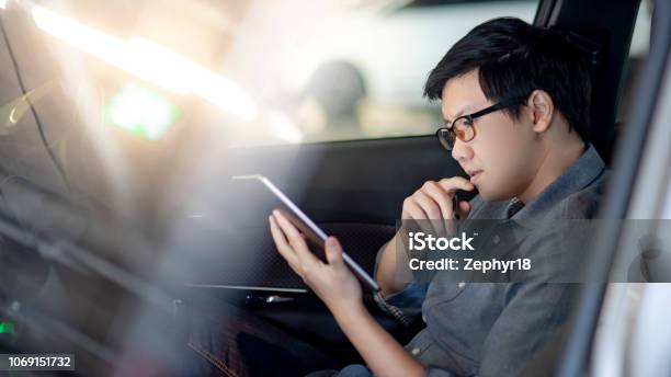 Young Asian Businessman With Glasses Reading News On Digital Tablet While Sitting On Driver Seat In His Car Business And Technology Concept Stock Photo - Download Image Now