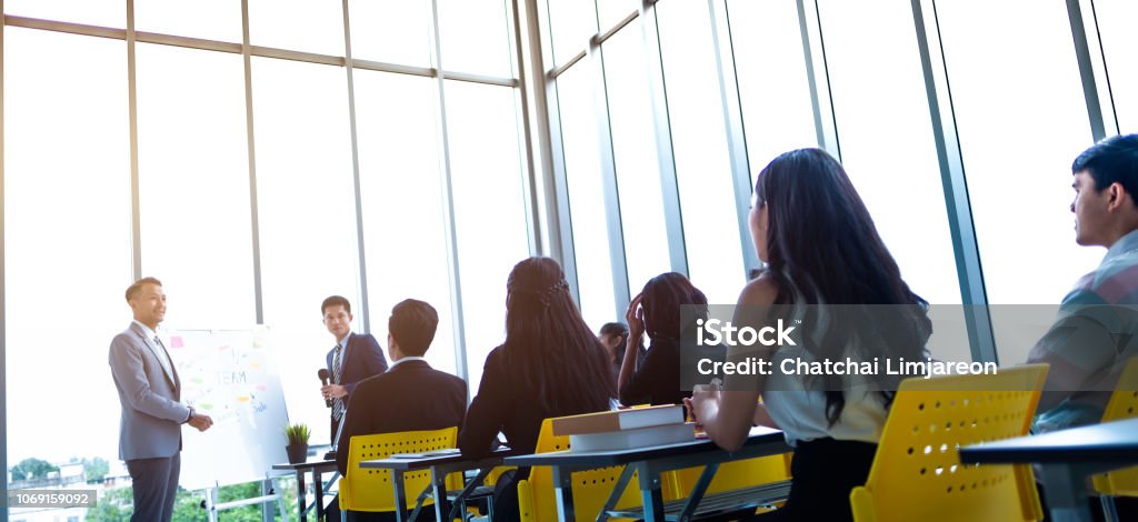 Group of attentive adult students with speaker giving a talk or trainer in classroom or seminar at business training to success of target. Education Training Class Stock Photo