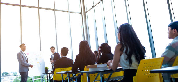 group of attentive adult students with speaker giving a talk or trainer in classroom or seminar at business training to success of target. - teaching seminar presentation classroom imagens e fotografias de stock