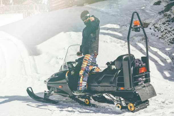 istock Bearded snowboarded poising on snowmobile. Snow patrol. Blurred background.Horizontal.Visual effects. 1069160252