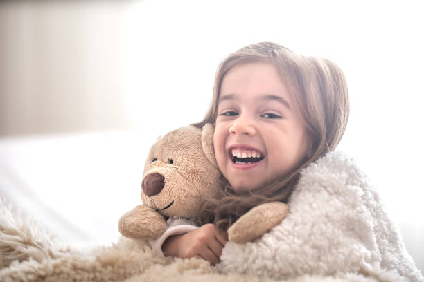 istock Little girl hugging bear toy on light background 1069170048
