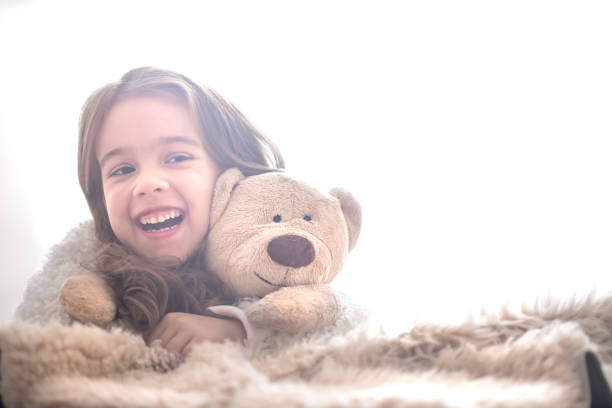 istock Little girl hugging bear toy on light background 1069171198