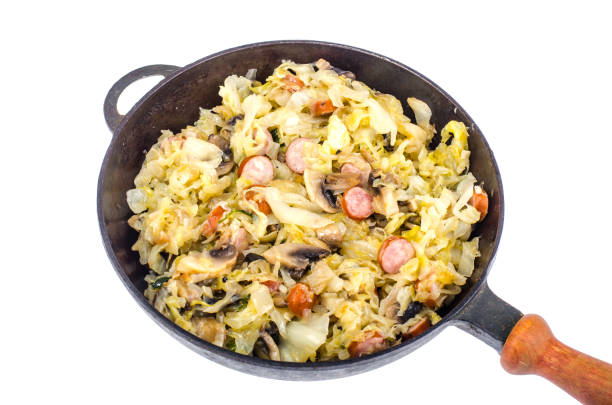 istock Frying pan with fried cabbage, sausages and mushrooms on white background 1069172508