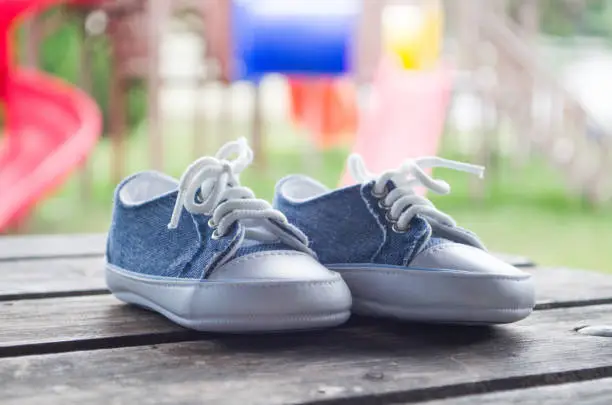 Blue-whitw baby shoes on a wooden table outdoors
