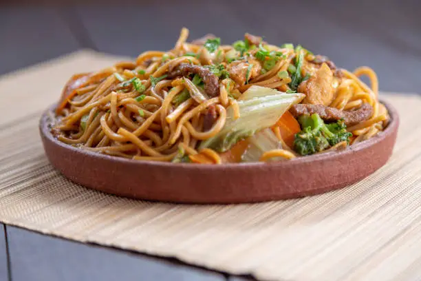 yakisoba, Japanese food composed of noodles, cubed stranded canes, carrots, yakisoba sauce and shoio sauce, bócolis, cauliflower and onion cut into cube, utilisar oriental cutlery, hashi