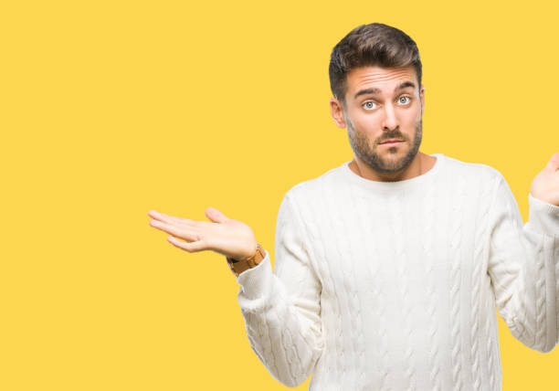 istock Young handsome man wearing winter sweater over isolated background clueless and confused expression with arms and hands raised. Doubt concept. 1069188254