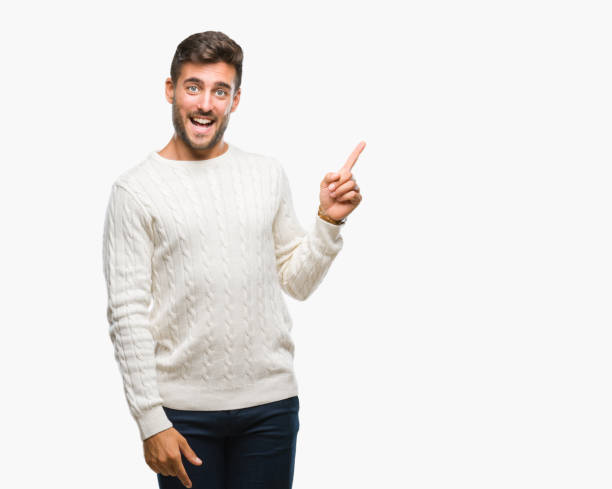 istock Young handsome man wearing winter sweater over isolated background with a big smile on face, pointing with hand and finger to the side looking at the camera. 1069189050