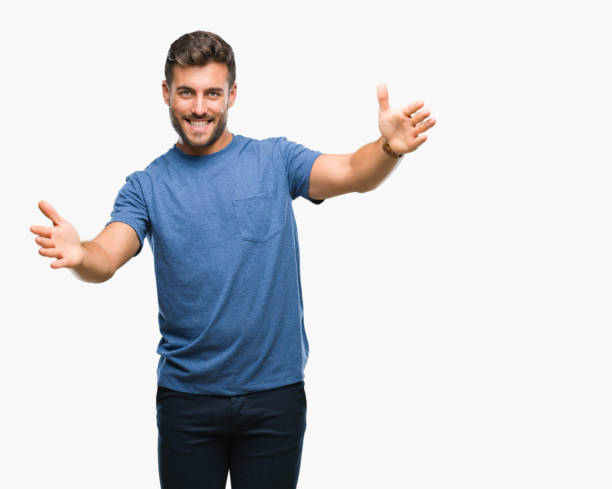 istock Young handsome man over isolated background looking at the camera smiling with open arms for hug. Cheerful expression embracing happiness. 1069189176