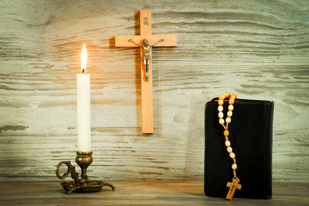 istock Lighted candle, crucifix, and a book with a rosary 1069191010
