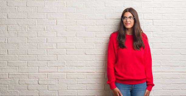 istock Young brunette woman standing over white brick wall smiling looking side and staring away thinking. 1069192322