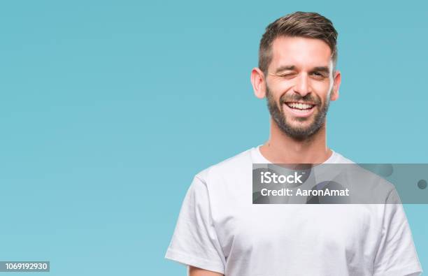 Young Handsome Man Over Isolated Background Winking Looking At The Camera With Sexy Expression Cheerful And Happy Face Stock Photo - Download Image Now