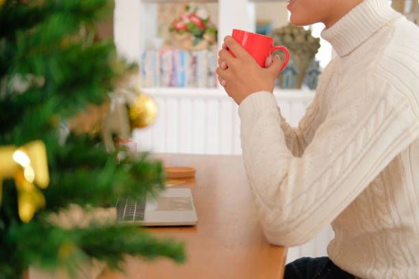 istock man holding coffee cup & using computer at home during christmas. xmas new year celebration 1069193046