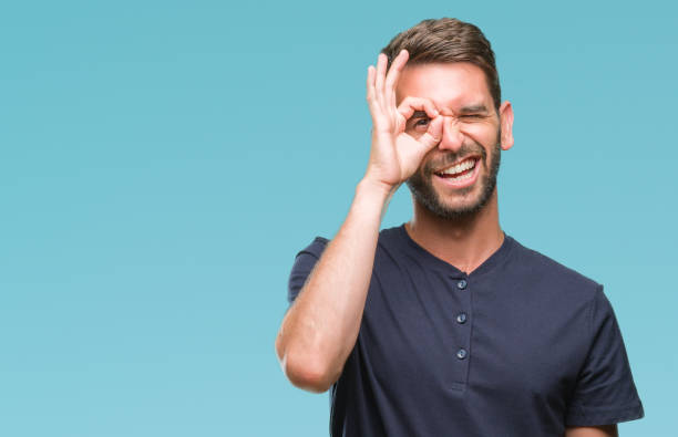 istock Young handsome man over isolated background doing ok gesture with hand smiling, eye looking through fingers with happy face. 1069193574