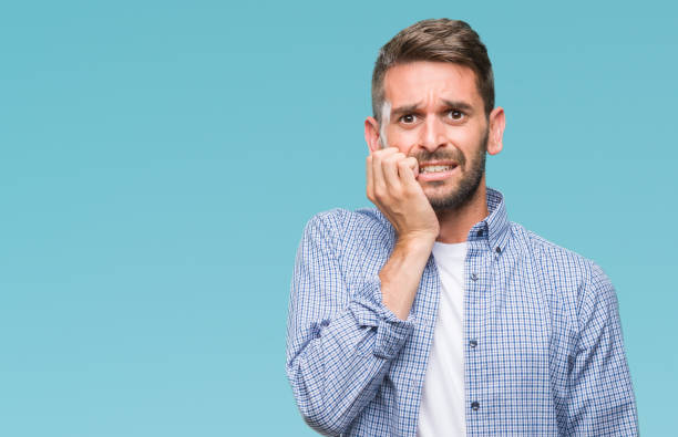 istock Young handsome man wearing white t-shirt over isolated background looking stressed and nervous with hands on mouth biting nails. Anxiety problem. 1069193744