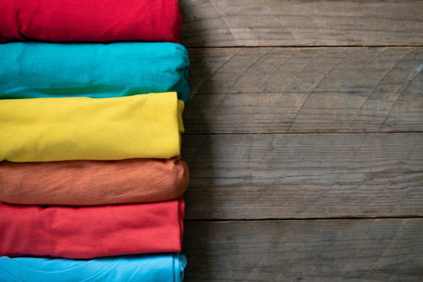 close up of rolled colorful clothes on wooden table background