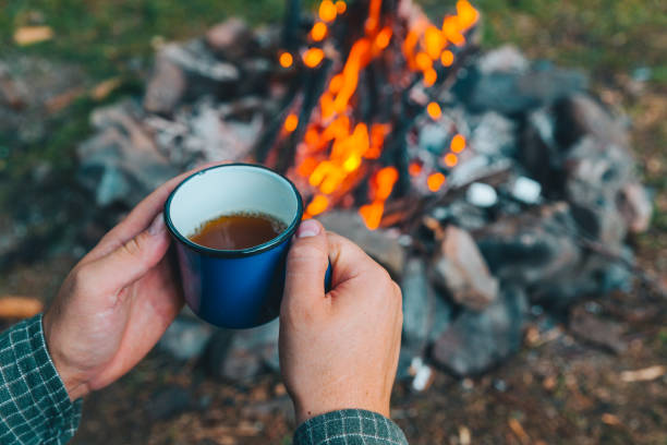 istock first point of view. man drinking tea in metal cup near camp fire 1069202142