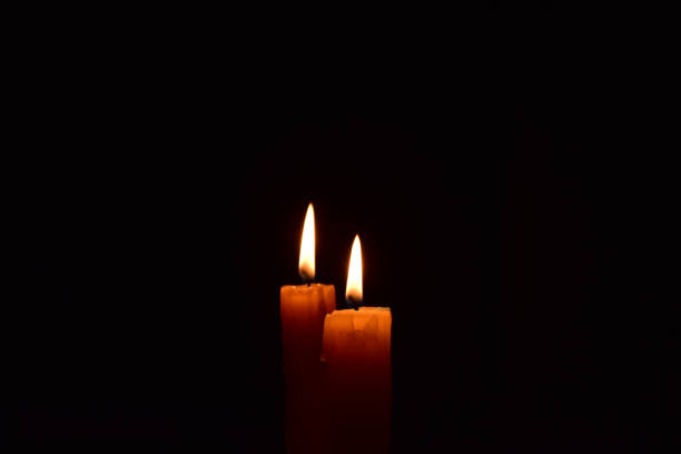 istock Yellow light candle burning brightly in the black background. 1069204982