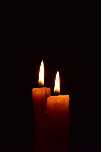 istock Yellow light candle burning brightly in the black background. 1069206052