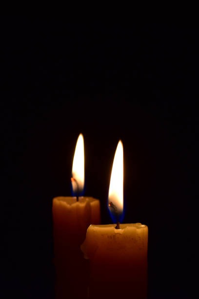 istock Yellow light candle burning brightly in the black background. 1069206088