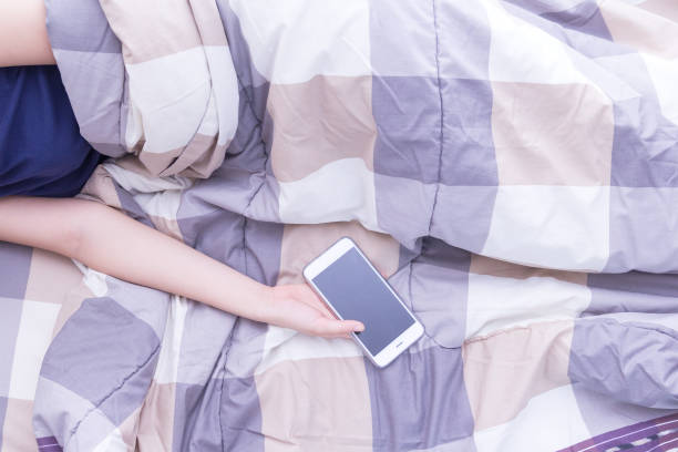 istock Woman sleeping and holding a mobile phone in the bed 1069209790