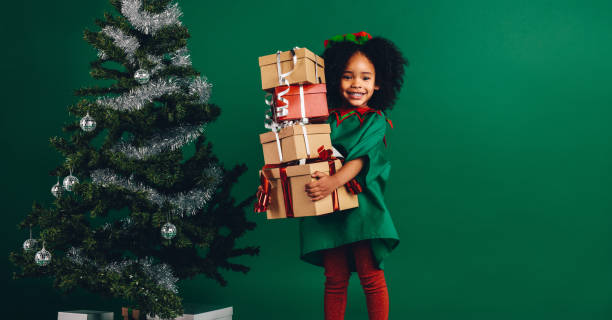 ragazzo sorridente che tiene in mano una pila di scatole regalo - christmas child foto e immagini stock