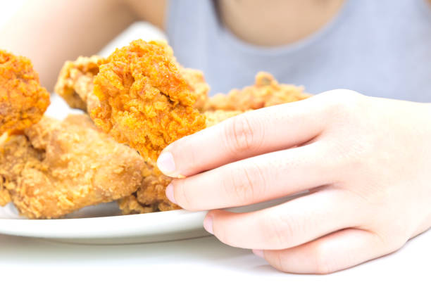 istock Woman holding and eatting fried chicken in white plate on white table 1069219202