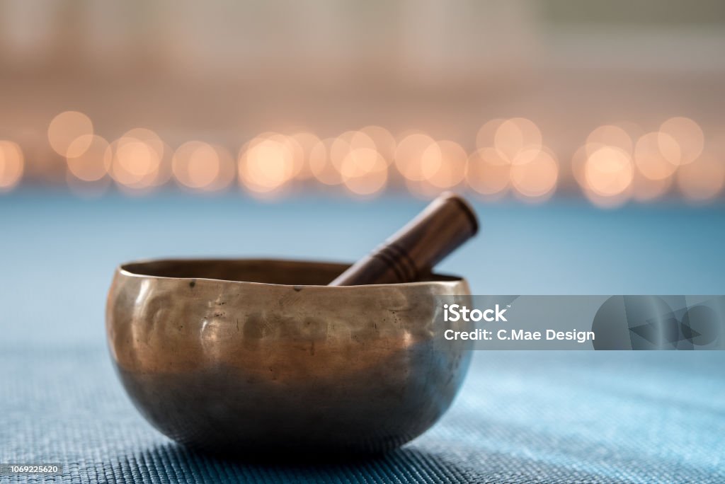 Singing bowl Tibetan musical instrument on yoga mat with lights in background Rin Gong Stock Photo