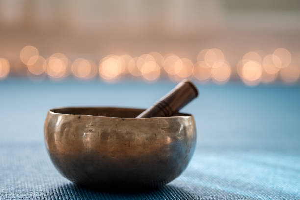 Singing bowl Tibetan musical instrument on yoga mat with lights in background tibet photos stock pictures, royalty-free photos & images