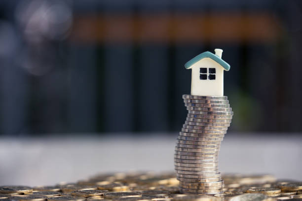 House model on coins stack. Concept for property ladder, mortgage and real estate investment . stock photo