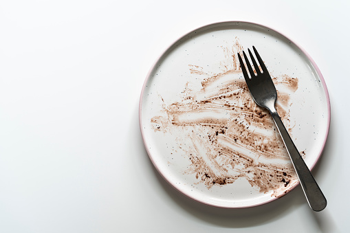 Dirty plate after a finished chocolate cake on white table