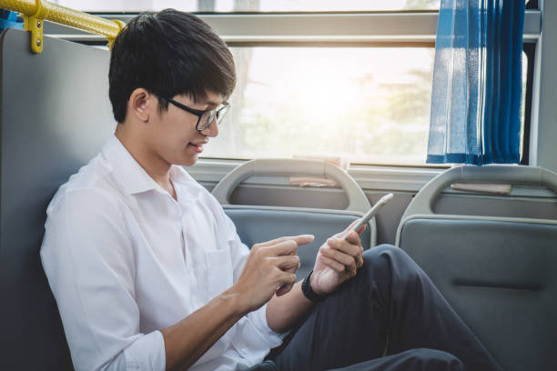 istock Young Asian man traveler sitting on a bus talking and using smartphone while smile of happy, transport, tourism and road trip concept 1069232876