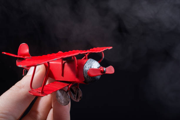 istock Hand holding a toy plane on black background 1069236034
