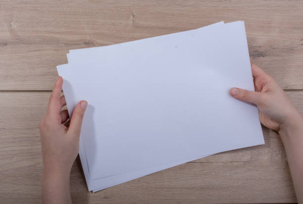 istock Hand holding sheets of paper on wooden background 1069236062