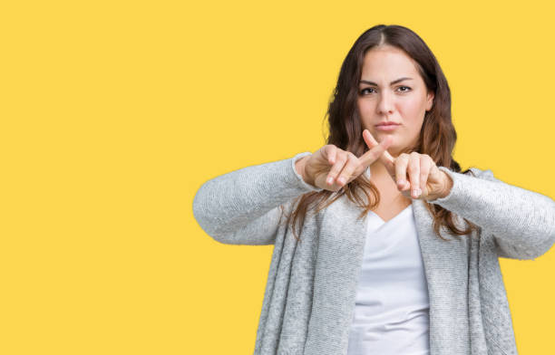 istock Beautiful plus size young woman wearing winter jacket over isolated background Rejection expression crossing fingers doing negative sign 1069237588