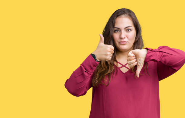 istock Beautiful plus size young woman over isolated background Doing thumbs up and down, disagreement and agreement expression. Crazy conflict 1069238218