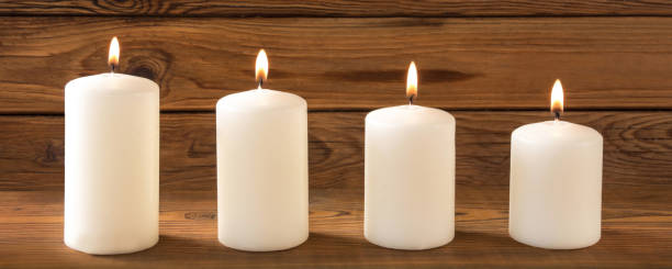 istock Four white candles against wooden background 1069238278