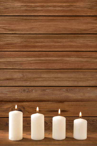 istock Four white candles against wooden background 1069238334