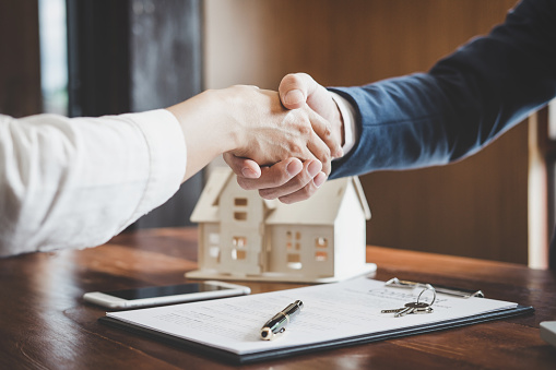 Real estate agent and customers shaking hands together celebrating finished contract after about home insurance and investment loan, handshake and successful deal.
