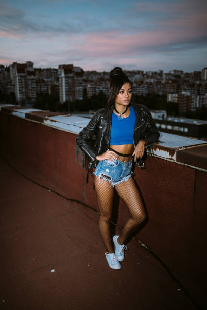 istock Beautiful woman with leather jacket leaning back on rooftop 1069240874
