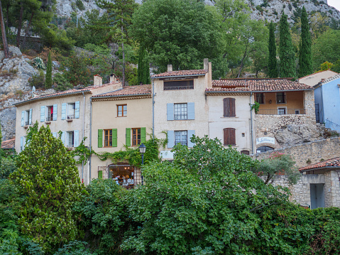 Moustiers-Sainte-Marie, France - August 8 2017: A picture of the houses and gardens along the river that runs through the town of Moestiers-Sainte-Marie.