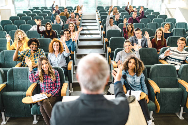 istock Happy college students raising their arms on a class at amphitheater. 1069245554