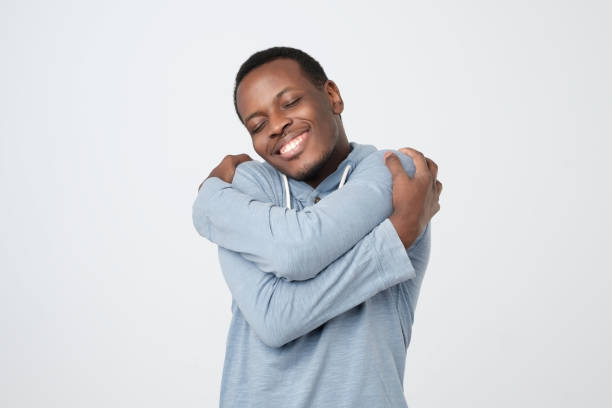 istock Funny playful african guy cuddling himself and smiling from pleasure 1069245652