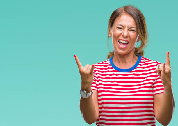 istock Middle age senior hispanic woman over isolated background shouting with crazy expression doing rock symbol with hands up. Music star. Heavy concept. 1069251116