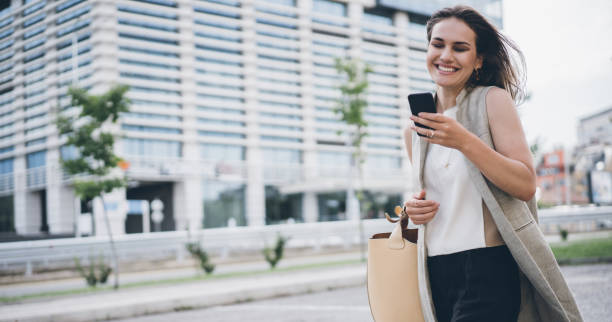 istock Young happy woman walking and texting 1069252334