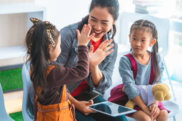 istock Teacher is reading story book to kindergarten students hi five 1069255044