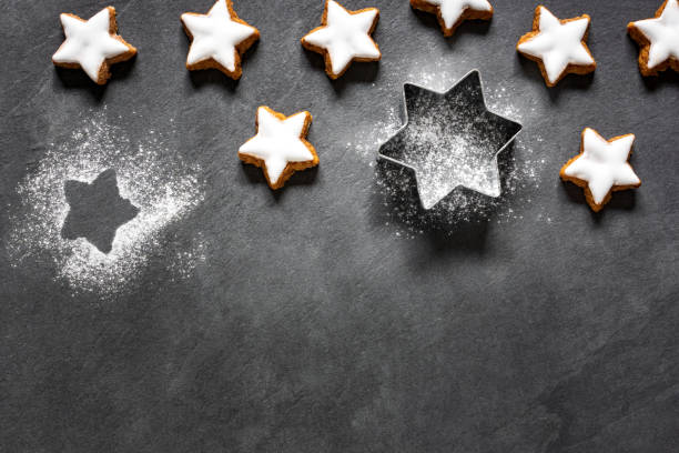 biscotti freschi a forma di stella di cannella con glassa su sfondo ardesia nera - zimtstern foto e immagini stock